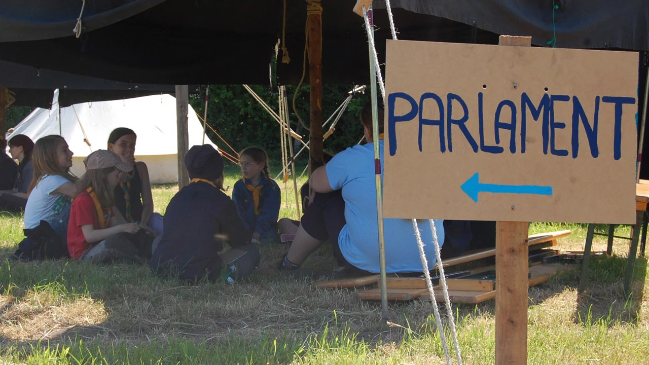 Eine Gruppe Pfadfinder*innen sitzt in einer Jurte mit einem Schild Parlament