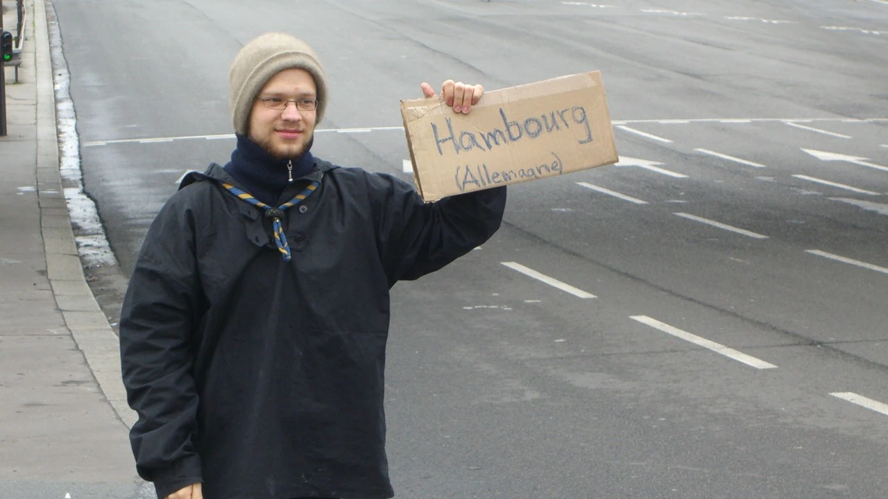 Pfadfinder beim Trampen mit Schild mit Aufschrift Hambourg Allemagne